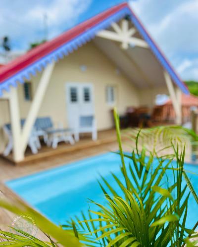 a house with a swimming pool in front of it at Bungalow Carioca Vue mer piscine privée au calme in Le Robert