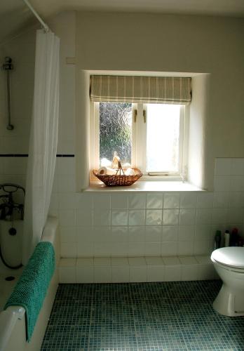 a bathroom with a window and a tub and a sink at Old Orchard Cottage in Colyton