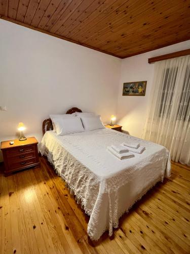 a bedroom with a bed with white sheets and two lamps at Bee Home - Holiday Cottage in Agia Effimia