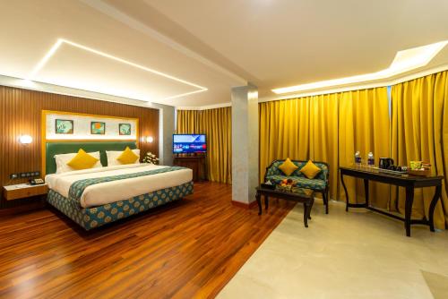 a hotel room with a bed and a desk and a television at Residency Tower in Trivandrum