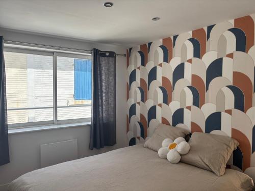 a bedroom with a bed with a patterned wall at maison proche plage et centre ville in Les Sables-dʼOlonne