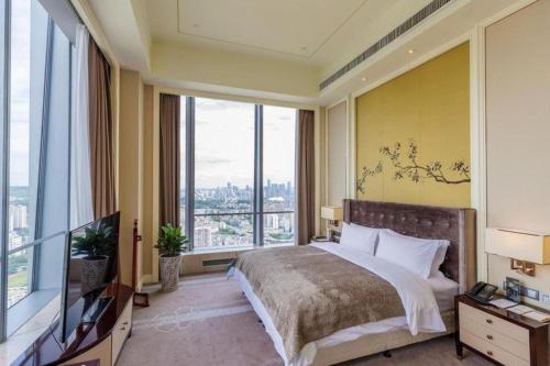 una camera da letto con un letto grande e grandi finestre di Ming Du Lakeside Hotel Nanning a Nanning