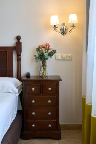 a vase of flowers on a dresser next to a bed at Hotel María de Molina in Úbeda