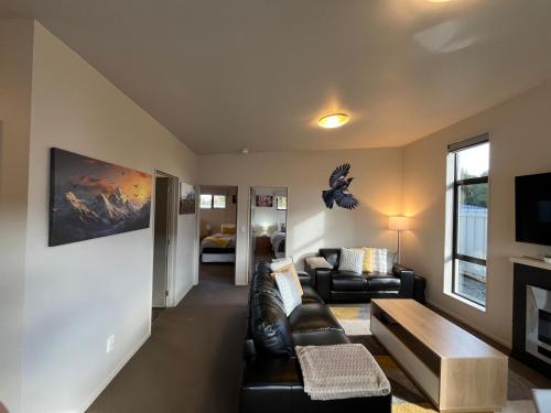 a living room with a leather couch and a tv at Spa, mountain views & a gas fireplace in Ohakune
