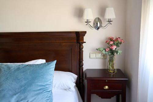 a bedroom with a bed and a vase of flowers on a table at Hotel María de Molina in Úbeda