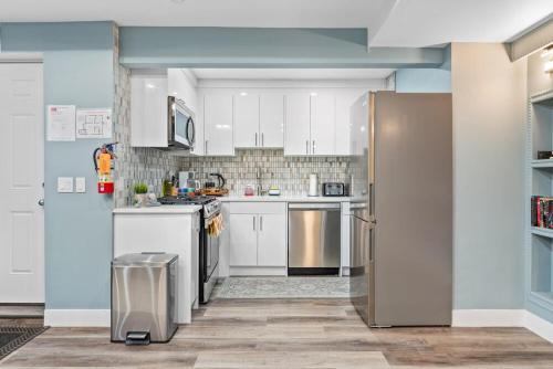 a kitchen with white cabinets and a stainless steel refrigerator at Private Family Entertainer's Suite in Calgary