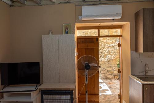 a room with a fan and a television and a door at Traditional Stone House in Vouni, Quiet Stay with Courtyard & BBQ in Vouni
