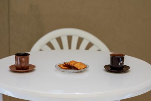 a white table with two cups of coffee and croissants at Traditional Stone House in Vouni, Quiet Stay with Courtyard & BBQ in Vouni