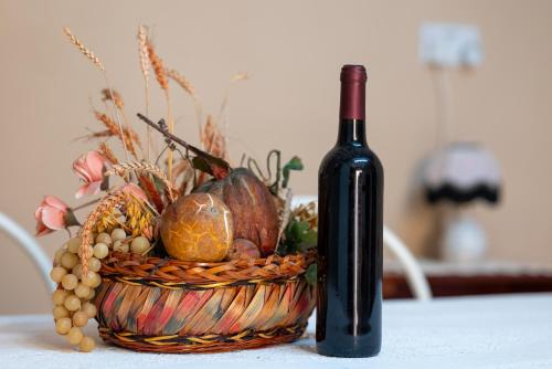 a bottle of wine sitting next to a basket of fruit at Traditional Stone House in Vouni, Quiet Stay with Courtyard & BBQ in Vouni