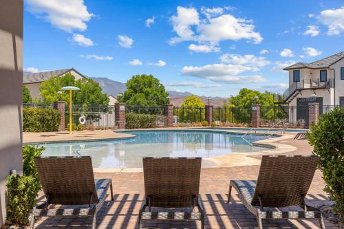 a swimming pool with two chairs and a fence at The Ella home in Hurricane