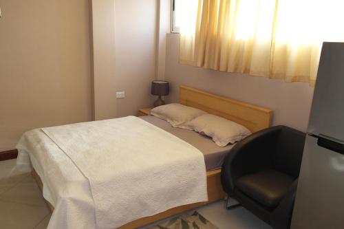 a small bedroom with a bed and a chair at Ridge Over Suite in Accra