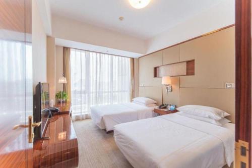 a hotel room with two beds and a television at Jinan Silver Plaza Quancheng Hotel in Jinan