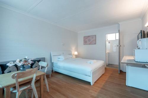 a white bedroom with a bed and a table at Motel Maroondah in Box Hill