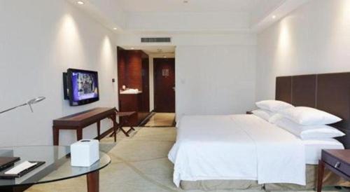 a hotel room with a white bed and a desk at New Century Grand Hotel Zhuji Yaojiang in Shaoxing