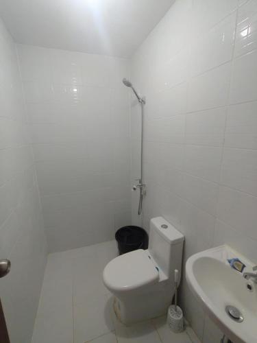 a white bathroom with a toilet and a sink at JV tRansient 24 in Ormoc