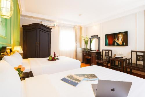 a hotel room with two beds and a laptop on a table at Sena Boutique Hotel & Travel in Hanoi