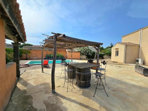 un patio avec une table et des chaises et une piscine dans l'établissement SORRA : Belle villa, piscine, jardin et plage à 5 minutes., au Grau-dʼAgde