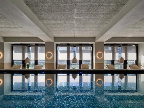 a swimming pool in a hotel with chairs and windows at Platinum Luxury Stays at Aston in Melbourne