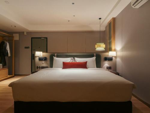 a bedroom with a large white bed with red pillows at Shō Hotel BreakX in Jelutong