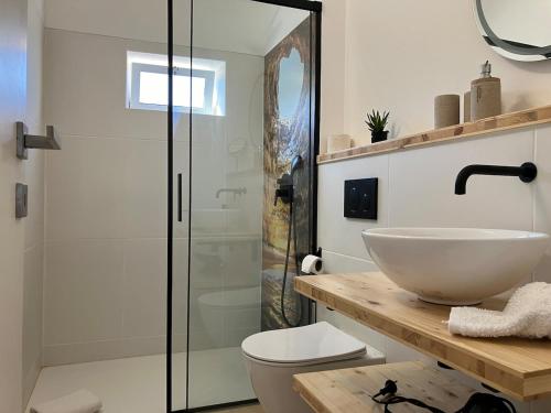 ein Badezimmer mit Waschbecken und Glasdusche in der Unterkunft Boutique holiday home "Casa da vida doce" I Private, quiet & stylish I Pool, garden, sea view I For families, friends & couples in Lagoa