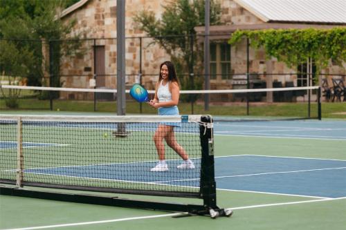 a woman standing on a tennis court holding a frisbee at Hyatt Regency Lost Pines Resort and Spa in Cedar Creek
