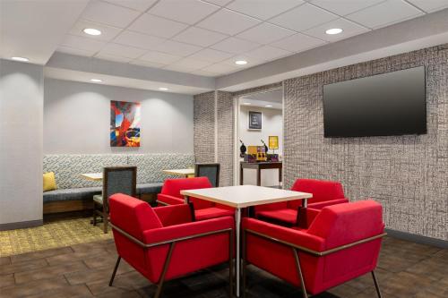 a waiting room with red chairs and a flat screen tv at Hampton Inn Las Vegas/North Speedway in Las Vegas