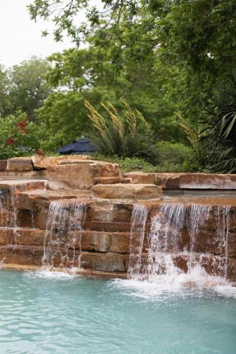 a waterfall in a swimming pool with water falling into the water at Hyatt Regency Lost Pines Resort and Spa in Cedar Creek