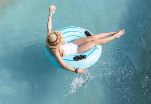 a woman in a hat laying on a raft in the water at Hyatt Regency Lost Pines Resort and Spa in Cedar Creek