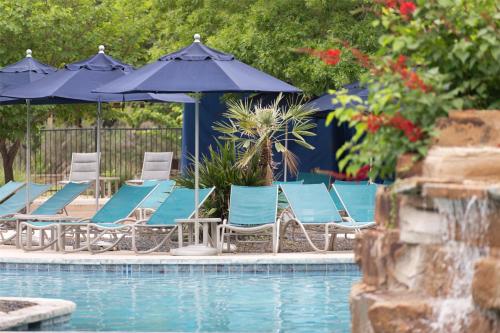 a group of chairs and umbrellas next to a pool at Hyatt Regency Lost Pines Resort and Spa in Cedar Creek