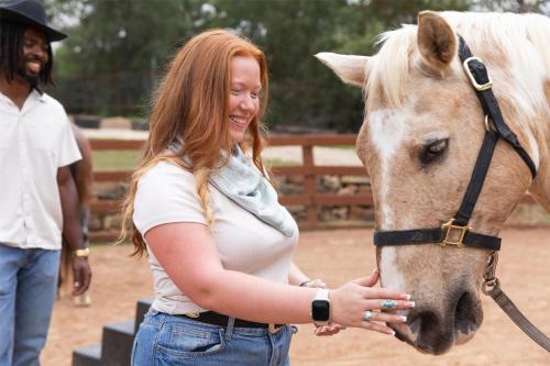 a woman is smiling while petting a horse at Hyatt Regency Lost Pines Resort and Spa in Cedar Creek