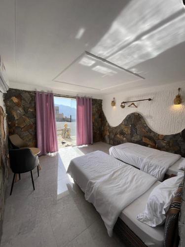 a bedroom with two beds and a stone wall at Balcony walk rest house Jabal shams in Sa‘ab Banī Khamīs