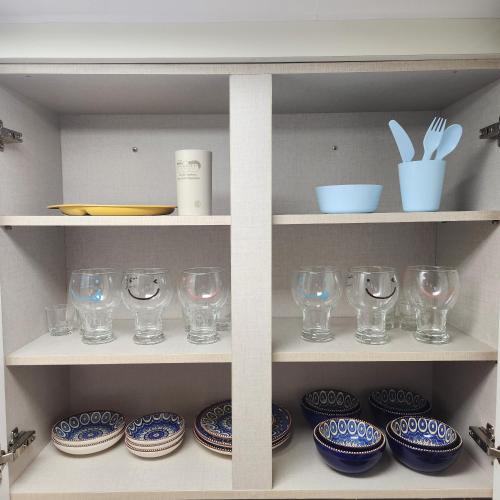 a shelf filled with glasses and plates and bowls at Lake House in Hwaseong