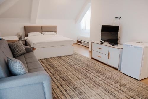 a living room with a couch and a bed and a tv at Potočari Han in Srebrenica