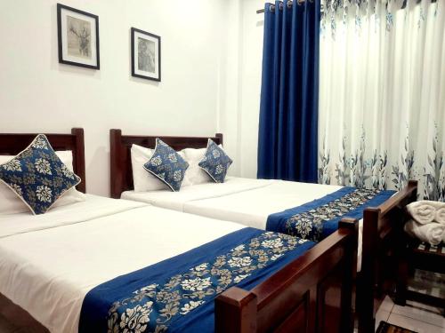 - 2 lits dans une chambre avec des rideaux bleus dans l'établissement Ivy Bungalow, à Nuwara Eliya