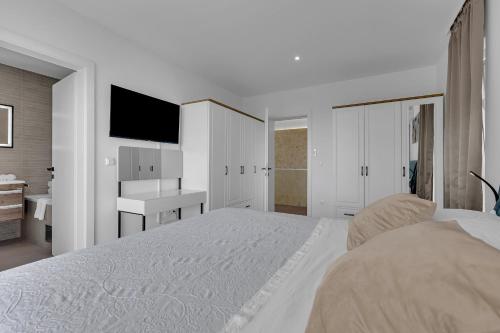 a white bedroom with a large bed and a television at Villa Solas Lux Makarska - Veliko Brdo in Veliko Brdo