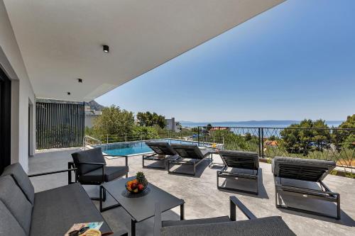 a patio with chairs and a table and a swimming pool at Villa Solas Lux Makarska - Veliko Brdo in Veliko Brdo