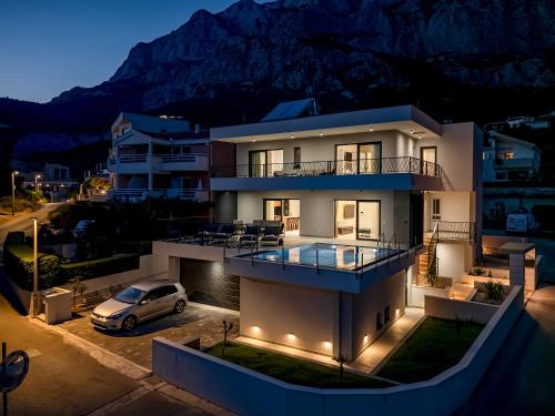 a house with a car parked in a parking lot at Villa Solas Lux Makarska - Veliko Brdo in Veliko Brdo