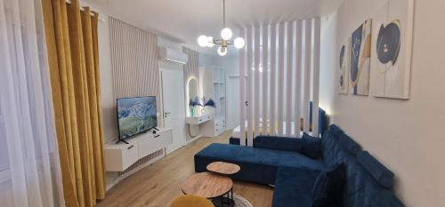 a living room with a blue couch and a tv at Juar Villa - Modern Apartments in Tirana