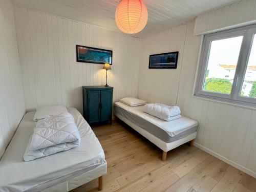 une chambre avec deux lits et une lampe et une fenêtre dans l'établissement Rue des Présidents - 2-4 pers - 300m de la mer, à Les Sables-dʼOlonne