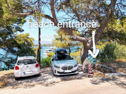a white car parked next to a white car parked under a tree at Stone Villa Hvar Ana Nikola Beach Park and Sea View in Jelsa