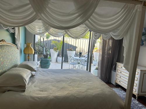 a bedroom with a canopy bed with a view of a patio at Koombana Retreat in Perth