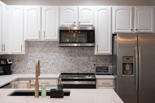a kitchen with white cabinets and a stainless steel refrigerator at Gorogeous Chic 2BDR Renovated Home near Downtown Sleeps 6 843 in Traverse City