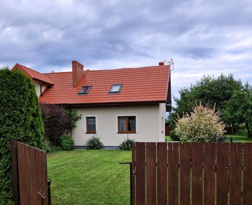 a white house with a red roof and a fence at Bez Pośpiechu Mazury in Suchy Róg