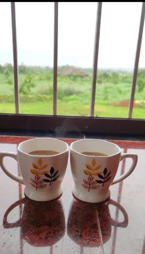 two cups sitting on a table in front of a window at Vana The Forest Farm in Saralgaon