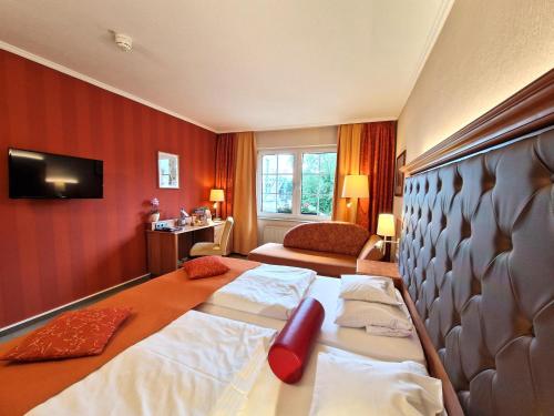a hotel room with a bed and a couch and a television at Hotel Zum Stein Wellness & Genuss Resort in Oranienbaum-Wörlitz