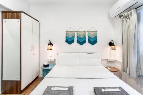 a white bedroom with a bed and a mirror at Tori 1BHK Bandra W by The Bombay Home Company in Mumbai