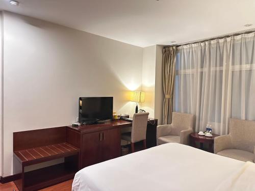 a hotel room with a bed and a desk with a television at Nesta Hotel Hanoi in Hanoi