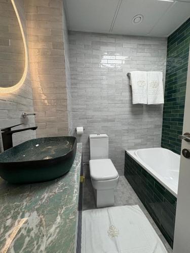 a bathroom with a black tub next to a toilet and a sink at Studio at Bab Al Bahr RAK in Ras al Khaimah