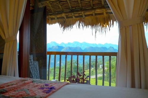 a bedroom with a large window with a view of the mountains at Pu Luong Jungle Lodge in Pu Luong