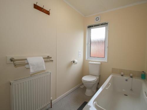 a bathroom with a tub and a toilet and a window at Snowdrop in Leominster